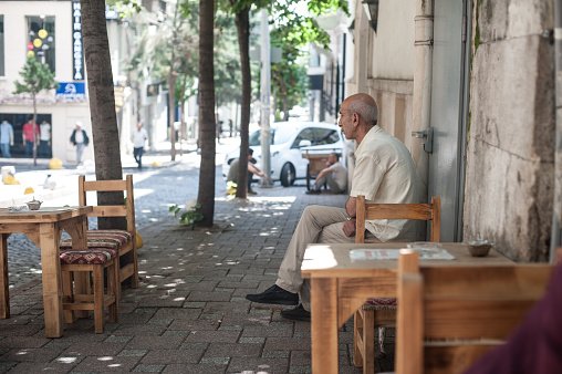 ISTANBUL, TURKEY – 03. JUNE 2019. An unidentified man drinks coffee in a national old-fashioned Turkish setting cafe on the street. Daily atmosphere in Turkey