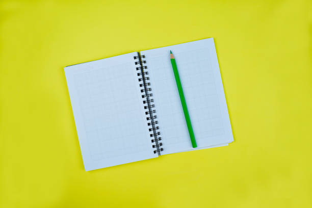 istock A green wood pencil crayon placed over a opened notebook and ready to write something 1214984173