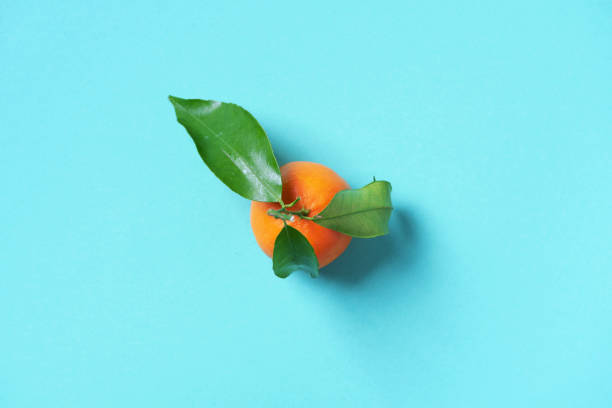 Tangerine or clementine with green leaf on blue background. Top view. Copy space. Christmas or New year concept