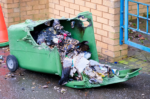 Wheelie bin vandalism on side burnt out by fire by vandals in council estate London arson attack uk