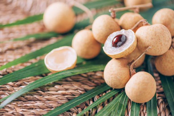 Longan fruits over palm leaves on rattan background. Copy space. Dimocarpus longan. Bunch of exotic longans. Tropical food concept. Longan fruits over palm leaves on rattan background. Copy space. Dimocarpus longan. Bunch of exotic longans. Tropical food concept longan stock pictures, royalty-free photos & images
