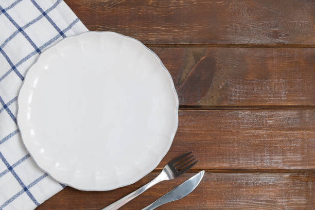 istock Blank flat plate with kitchen napkin on wooden table 1214988573
