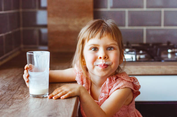 happy little girl drinking milk or another dairy product - milk child drinking little girls imagens e fotografias de stock