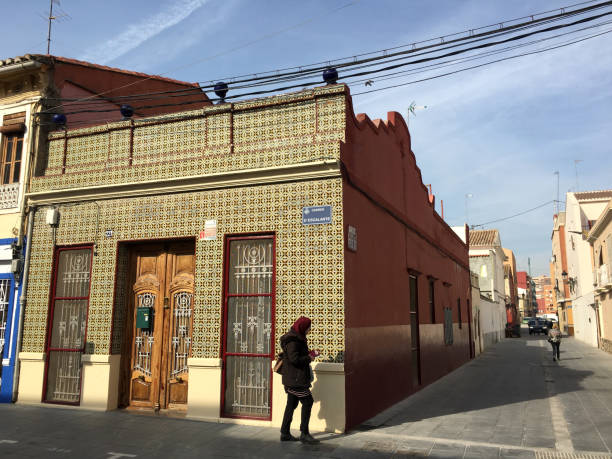 Valencia, Spain - March 12, 2020: Arab woman holding smartphone walking in the streets of El Cabanyal district. This neighborhood is located near the sea and is home for a lot of immigrants