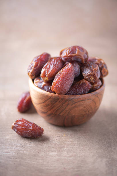 Dried date fruit in wooden bowl on wood textured background. Copy space. Superfood, vegan, vegetarian food concept. Macro of dates texture, selective focus. Healthy snack Dried date fruit in wooden bowl on wood textured background. Copy space. Superfood, vegan, vegetarian food concept. Macro of dates texture, selective focus. Healthy snack. superfruit stock pictures, royalty-free photos & images