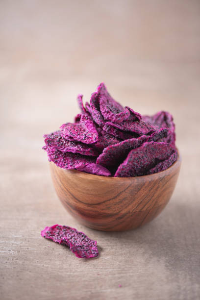 tranches séchées de fruits de dragon roses, pitaya dans un bol en bois sur fond texturé en bois. copier l’espace. superfood, végétalien, concept de nourriture végétarienne. macro de pitahaya, texture, mise au point sélective. collation saine. - carbohydrate ingredient food state choice photos et images de collection