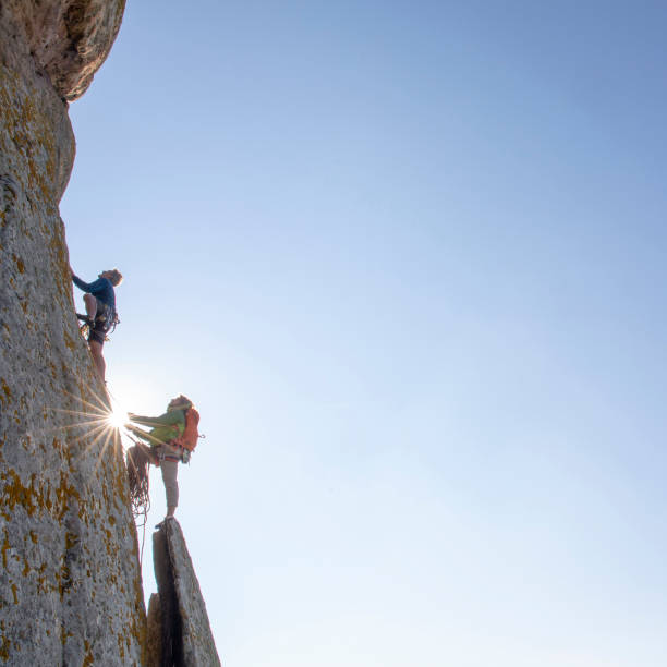 One man is climbing while the other belays