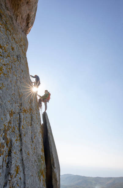 les grimpeurs de montagne montent la paroi rocheuse au lever du soleil - climbing rock climbing rock mountain climbing photos et images de collection
