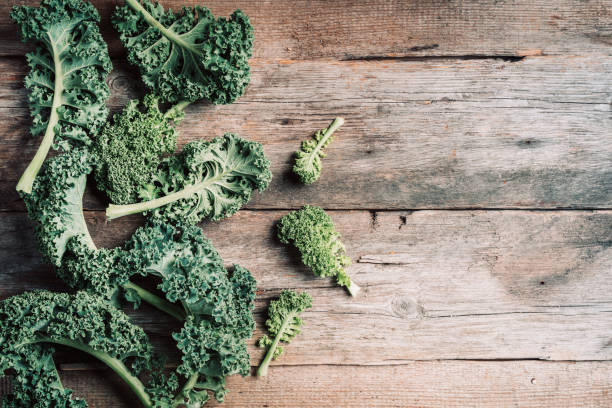 istock Fresh green curly kale on wooden background. Top view, copy space. Zero waste, organic vegetables concept. Vegan and vegetarian diet food. 1214990356