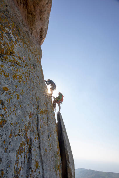 istock Mountain climbers ascend rock face at sunrise 1214990395