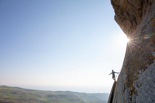 El alpinista asciende la cara de roca al amanecer photo
