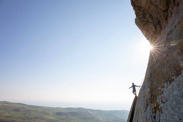 Mountain climber ascends rock face at sunrise