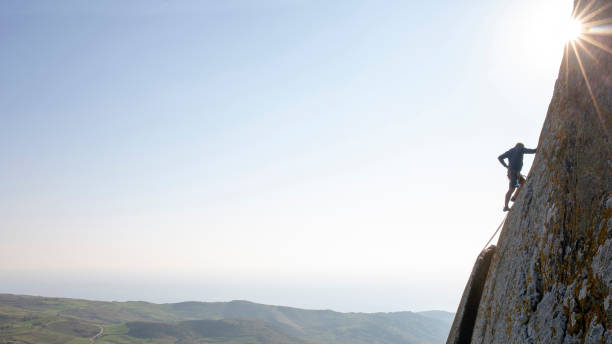 istock Mountain climber ascends rock face at sunrise 1214990412