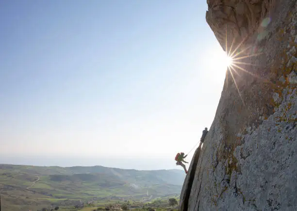 Photo of Mountain climbers ascend rock face at sunrise