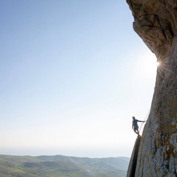 istock Mountain climber ascends rock face at sunrise 1214990521