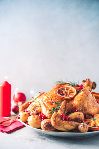 istock Roasted chicken with festive decoration, candles, light bokeh on concrete background. Traditional New Year holiday or Christmas celebration dish. Friends or family dinner. Festive Christmas table. 1214991477
