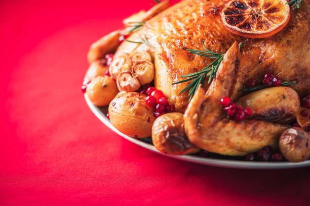 istock Roasted chicken with oranges, rosemary and cranberries on plate over red background. Traditional Thanksgiving or Friendsgiving holiday celebration dish. Friends or family dinner. Festive Christmas table. 1214991485