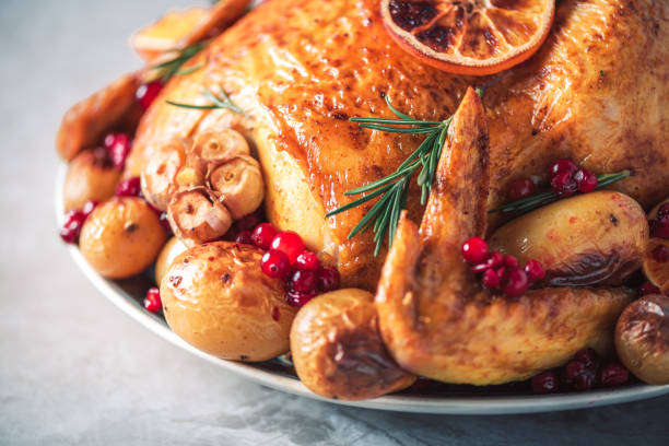 istock Roasted chicken with oranges, rosemary and cranberries on plate over concrete background. Traditional Thanksgiving or Friendsgiving holiday celebration dish. Friends or family dinner. Festive Christmas table. 1214991495