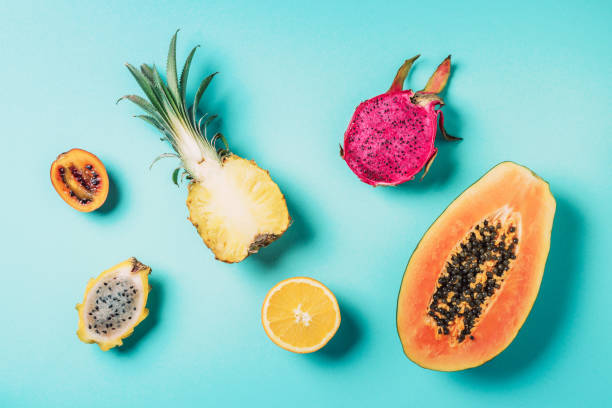 Creative layout made of exotic fruits - papaya, pineapple, dragon fruit, pitahaya, tamarillo fruit on blue background. Flat lay. Top view. Copy space. Summer food, tropical fruits concept. Vegan, fructorian diet. diseño creativo hecho de frutas exóticas - papaya, piña, fruta de dragón, pitahaya, fruta tamarillo sobre fondo azul. estaba plano. vista superior. copiar espacio. comida de verano, concepto de frutas tropicales. dieta vegana y fructoriana