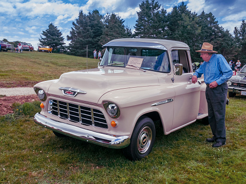 Chester, Nova Scotia, Canada - August 6, 2011 : 1955 Chevrolet 3100 pickup truck at Annual Graves Island Car Show at Graves Island Provincial Park, Chester, Nova Scotia, Canada. Senior adult man leans on the truck's door and speaks with the driver.