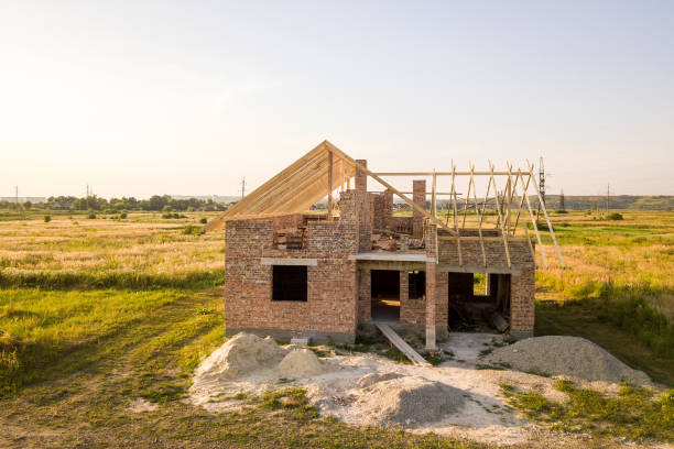 istock Unfinished brick house with wooden roof structure under construction. 1214998045
