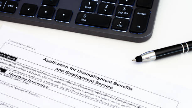 Application for employment benefits form with computer keyboard and pen on white background. Unemployment rate has risen sharply in United States due to closed business caused by corona virus outbreak stock photo