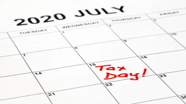 Taxes due date is set for 15th July 2020 due to corona virus outbreak. Calendar page with Tax Day written in red, remainder to pay taxes. Filling and payment was extended by the government.