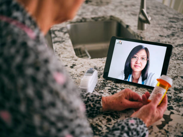 seniorin auf virtuellem arztbesuch - abstand halten infektionsvermeidung fotos stock-fotos und bilder