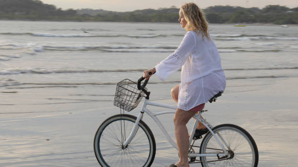 istock Woman bikes along tropical beach at sunrise 1215002502