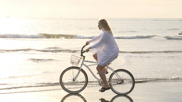 istock Woman bikes along tropical beach at sunrise 1215002506