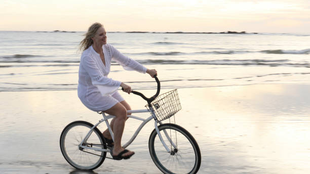 istock Woman bikes along tropical beach at sunrise 1215002525