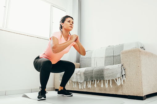 Young man working out at home doing squats