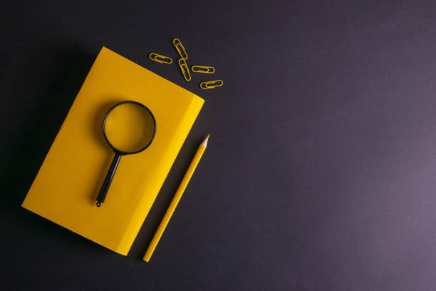 gelber bleistift, gelbe notebook-brille, stifte, büropapier und eine lupe auf schwarzem hintergrund - ruler ballpoint pen pen isolated stock-fotos und bilder