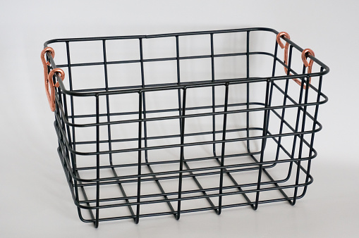 Black metal storage wire basket with bronze color handles white background