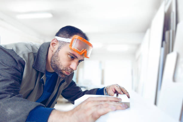 istock Carpenter doing quality control on white glossy melamine with protective eyewear 1215006293