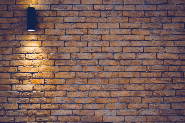 istock A section of a brown brick wall with an artificial light lamp. 1215007068