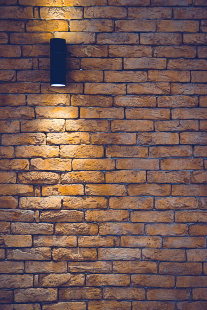 istock A section of a brown brick wall with an artificial light lamp. 1215009123