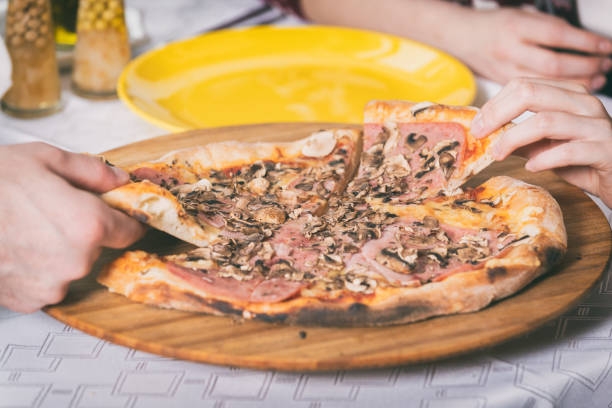 istock hands taking pieces of pizza from a plate 1215009230