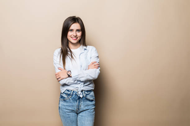 istock Charming brunette woman standing with hands folded, looking at camera, isolated over beige background 1215009238