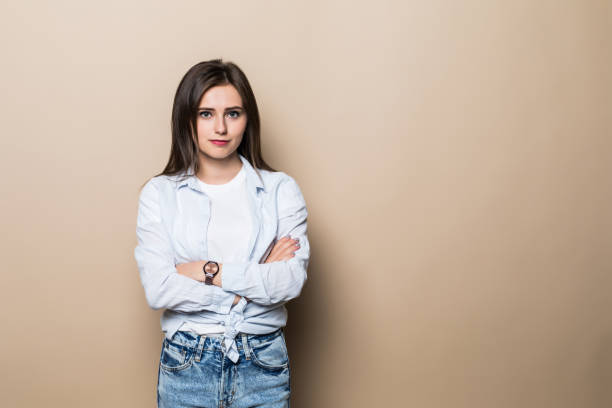 istock Charming brunette woman standing with hands folded, looking at camera, isolated over beige background 1215009270
