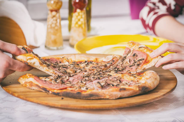 istock hands taking pieces of pizza from a plate 1215009340