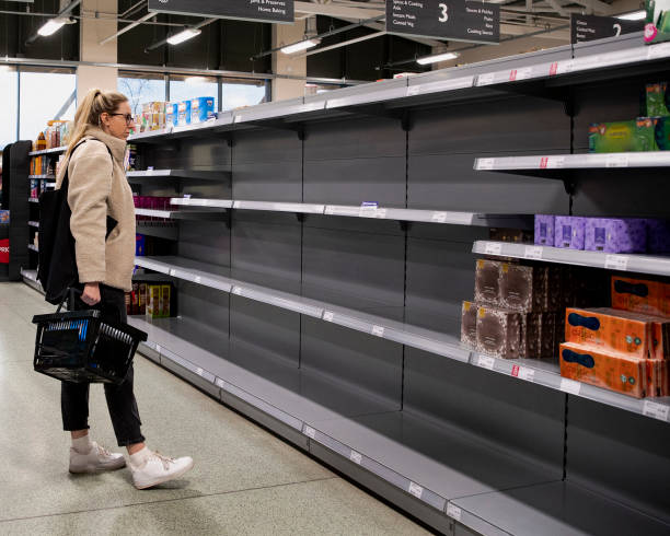 Panic Buying A young Caucasian female stands looking concerned at the empty shelves in a supermarket. shelf stock pictures, royalty-free photos & images