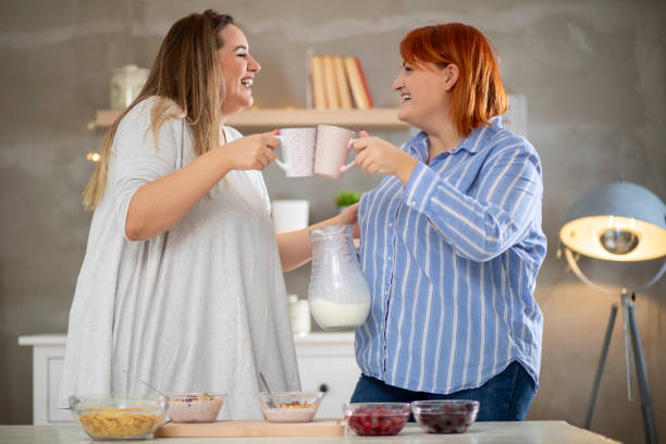 istock Young smiling plus size women preparing breakfast and drinking coffee. 1215011597