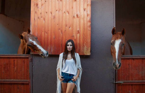 istock Beautiful woman posing between two horses 1215012760