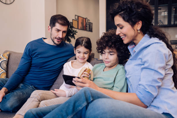 istock Young couple spending time at home with their children, using a smartphone 1215013181
