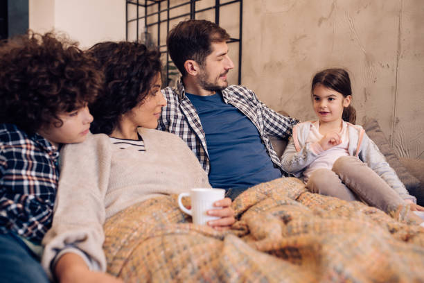 istock Young couple and their two kids spending time together on the sofa 1215013224