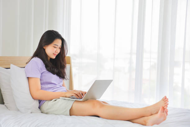 istock Young pretty girl working from home on her bed using computer laptop to access her work online 1215016476
