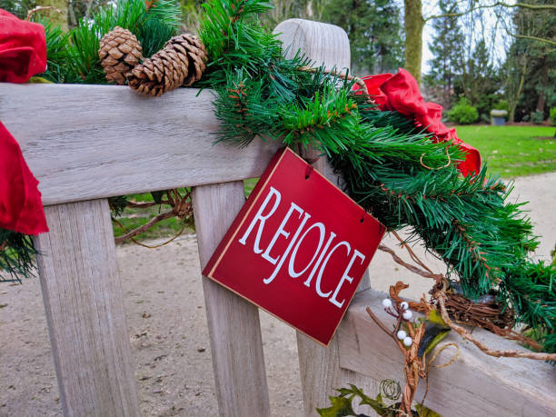 istock Rejoice sign surrounded by Christmas decor, draped on a wooden park bench 1215016607