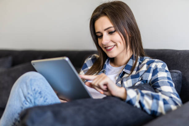 istock Young woman relaxing on a sofa while touching a tablet in a living room 1215021197