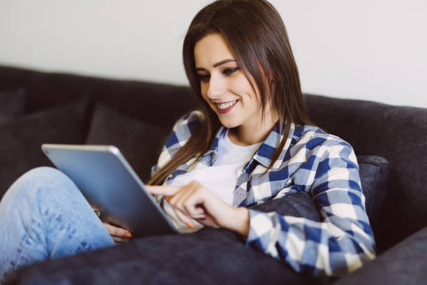 istock Young beautiful woman with tablet on sofa at home 1215023099